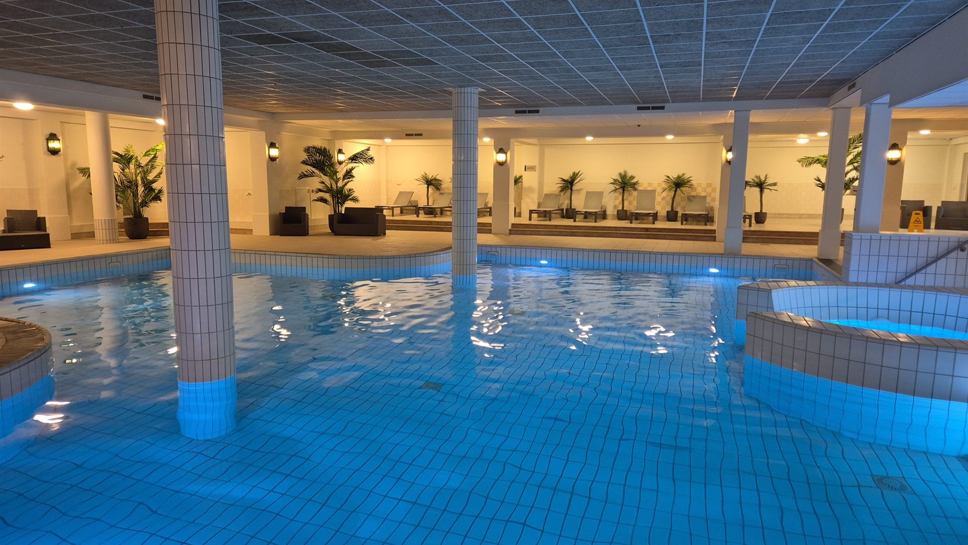 Het binnenbad van Hotel Heerlickheijd van Ermelo met warme verlichting en palmen